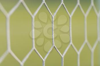 Soccer or Football Net Background - View From Behind the Goal With Blurred Stadium and Field Pitch