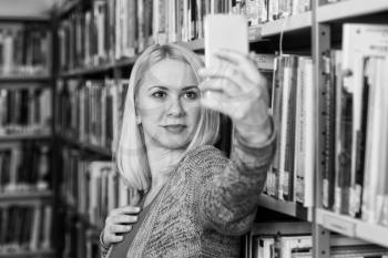 Portrait of a Happy Blonde Woman in Library at the University and Taking Selfies With Mobile Phone