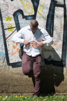 Portrait of a Young Physically Fit Man in White T-shirt Showing His Well Trained Body - Muscular Athletic Bodybuilder Fitness Model Posing After Exercises In Front Of A Graffiti Wall