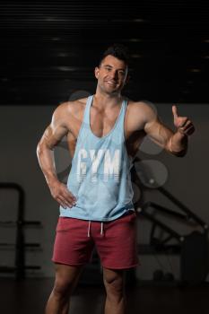 Portrait Of A Young Physically Fit Man In Blue Undershirt Showing Thumbs Up - Muscular Athletic Bodybuilder Fitness Model Posing After Exercises
