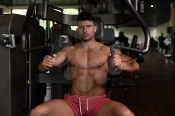 Handsome Muscular Fitness Bodybuilder Doing Heavy Weight Exercise For Chest On Machine With Cable In The Gym