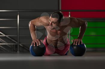 Handsome Young Man Doing Pushups With Medicine Ball As Part Of Bodybuilding Training
