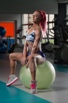 Attractive Woman Resting On Ball After Exercise In Fitness Center