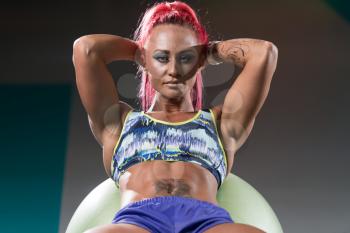 Young Woman Athlete Doing Abs Exercise On Ball As Part Of Bodybuilding Training