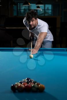 Young Man Lining To Hit Ball On Pool Table