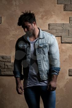 Cool Fashion Man in Blue Jeans Standing and Looking Away - Against Brick Wall on Copy Space