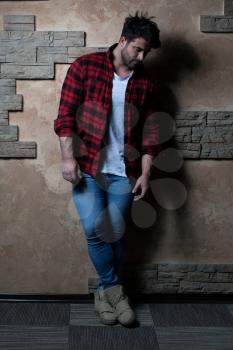 Cool Fashion Man in Blue Jeans Standing and Looking Away - Against Brick Wall on Copy Space