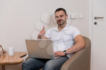 Handsome Man Sitting at Living Room Table Using Laptop Computer at Home