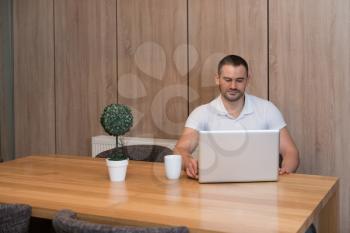 Handsome Man Sitting at Living Room Table Using Laptop Computer at Home