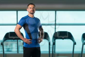 Portrait Of Personal Trainer In Sports Outfit In Fitness Center Gym Standing Strong