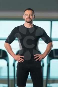 Portrait Of Handsome Personal Trainer Wearing Sportswear In Fitness Center Gym Standing Strong