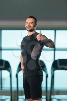 Handsome Personal Trainer Showing Thumbs Up Sign In A Fitness Center Gym Standing Strong