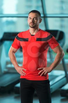 Portrait Of Handsome Personal Trainer Wearing Sportswear In Fitness Center Gym Standing Strong