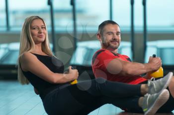 Young Woman And Man Doing Exercise With Kettle Bell In The Gym