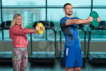 Young Woman And Men Doing Exercise With Weights In The Gym