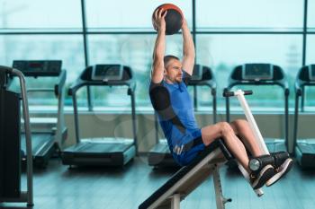 Young Fitness Man Working Out Abs With Fitness Ball On Adjustable Bench In Gym Center