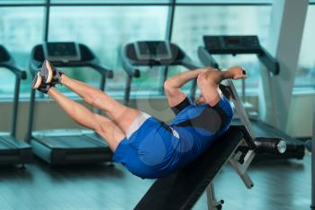 Young Fitness Man Working Out Abs On Adjustable Bench In Fitness Center