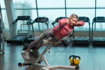Young Fitness Woman Working Out Back On Roman Chair In Fitness Center