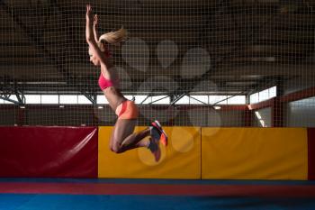 Female Athlete Performing a Long Jump in Gym - One of the Best Jumping Exercise for Vitality