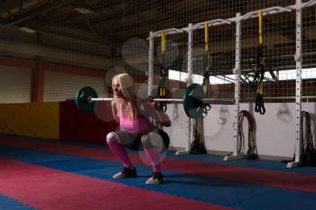 Young Woman Performing Barbell Squats - One Of The Best Bodybuilding Exercise For Legs