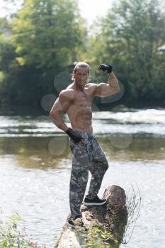 Healthy Mature Tattoo Man Standing Strong Outdoors In Nature And Flexing Muscles - Muscular Athletic Bodybuilder Fitness Model Posing After Exercises