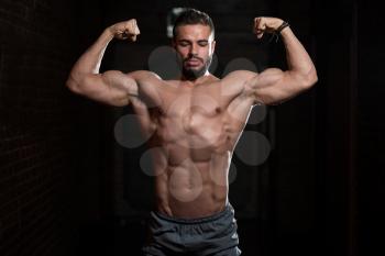 Handsome Young Model Standing Strong in the Fitness Center and Flexing Muscles - Muscular Athletic Bodybuilder Man Posing After Exercises
