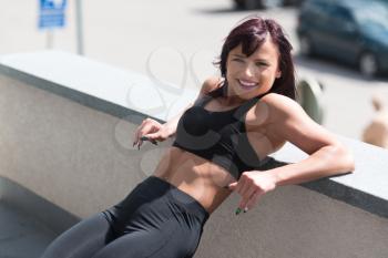 Attractive Woman Resting On Concrete Outdoors After Exercise In Fitness Center