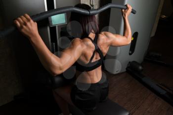Woman Working Out Back In A Gym On Machine With Cable