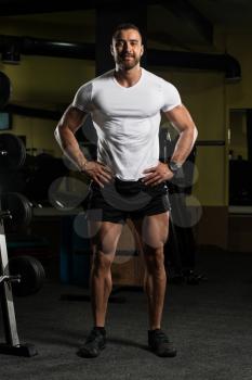 Handsome Young Man Standing Strong In White T-shirt And Flexing Muscles - Muscular Athletic Bodybuilder Fitness Model Posing After Exercises