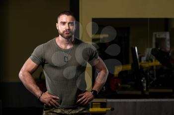 Handsome Man Standing Strong In Green T-shirt And Army Pants Flexing Muscles - Muscular Athletic Bodybuilder Fitness Model Posing After Exercises