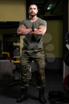 Portrait Of A Young Physically Fit Man Showing His Well Trained Body In Green Shirt and Army Pants - Muscular Athletic Bodybuilder Fitness Model Posing After Exercises