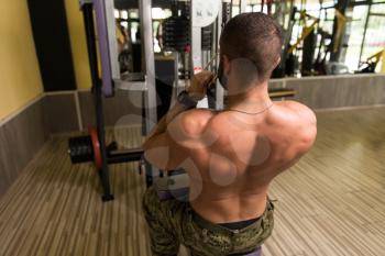 Handsome Bodybuilder Doing Heavy Weight Exercise For Back On Machine In Army Pants