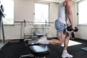 Athlete Working Out Hamstrings In A Gym With Dumbbells