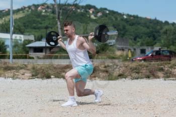 Athlete Working Out Legs In Nature With Barbell