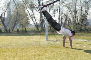 Attractive Man Doing Crossfit With Trx Fitness Straps in City Park Area - Training and Exercising for Endurance - Healthy Lifestyle Concept Outdoor