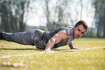 Young Man Doing Pushups in City Park Area - Training and Exercising for Endurance - Fitness Healthy Lifestyle Concept Outdoor