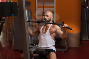 Handsome Bodybuilder Doing Heavy Weight Exercise For Back On Machine In Gym