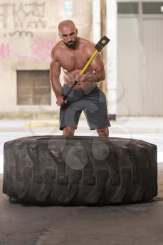 Athletic Man Hits Tire - Workout At Gym With Hammer And Tractor Tire