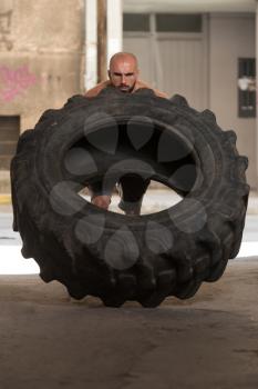 Young Muscular Man With Truck Tire Doing Crossfit Style Workout Turning Tire Over