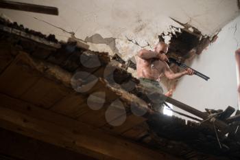 Action Hero Muscled Man Holding Machine Gun - Standing In Abandoned Building Wearing Army Pants