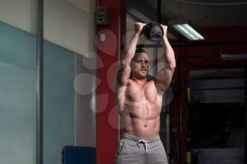 Young Man Working Out With Kettle Bell In A Dark Gym - Bodybuilder Doing Heavy Weight Exercise With Kettle-bell