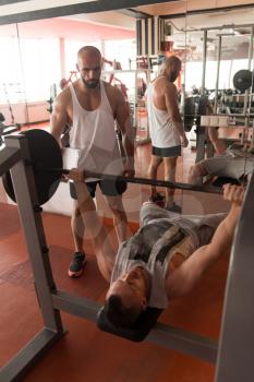Personal Trainer Showing Young Man How To Train Chest Exercise With Barbell In A Health And Fitness Concept