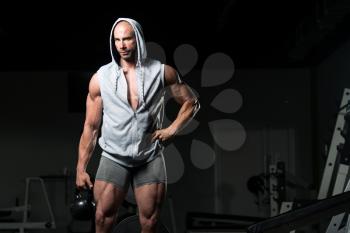 Man Working Out With Kettle Bell In A Dark Gym - Bodybuilder Doing Heavy Weight Exercise With Kettle-bell