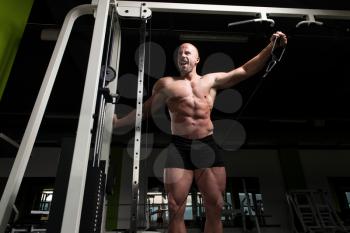 Muscular Fitness Bodybuilder Doing Heavy Weight Exercise For Shoulders On Cable Machine In The Gym