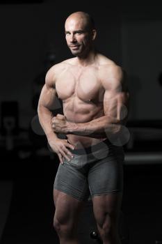 Handsome Young Man Standing Strong In The Gym And Flexing Muscles - Muscular Athletic Bodybuilder Fitness Model Posing After Exercises