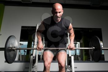 Bodybuilder Doing Heavy Weight Exercise For Back With Barbell In Modern Gym