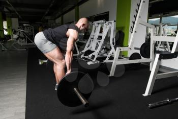 Bodybuilder Doing Heavy Weight Exercise For Back With Barbell In Modern Gym