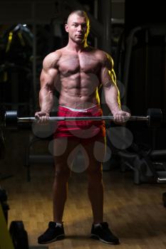 Athlete In The Gym Performing Biceps Curls With A Barbell