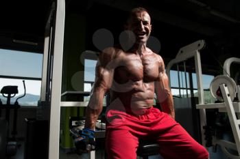 Bodybuilder Doing Heavy Weight Exercise For Trapezius On Machine