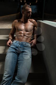 Portrait of a Young Physically Fit Man Showing His Well Trained Body On Stairs - Muscular Athletic Bodybuilder Fitness Model Posing After Exercises on Wall Near the Wall - a Place for Your Text